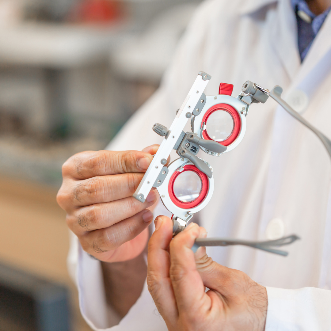 Optometrist holding a red trial lens frame for eye exams.